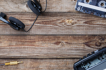 Image showing Cassette tape, cassette player and headphones over wooden table. top view.