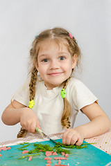 Image showing Little six year old girl trying to cut the greens at the kitchen table