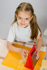 Image showing The little girl at the table t grated cheese