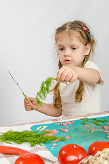 Image showing Little six year old girl looking at sprig of parsley is holding in his hand