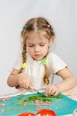Image showing Little six year old girl intently trying to cut with a knife green kitchen table