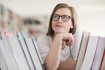 Image showing portrait of famale student selecting book to read in library