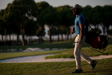 Image showing golfer  walking and carrying golf  bag at beautiful sunset