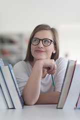 Image showing portrait of famale student selecting book to read in library