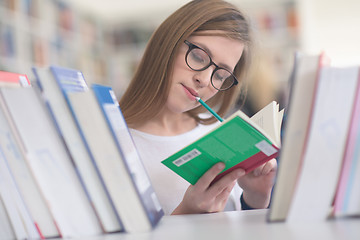 Image showing portrait of famale student selecting book to read in library