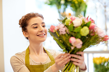 Image showing smiling florist woman making bunch at flower shop