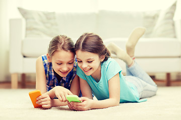 Image showing happy girls with smartphones lying on floor