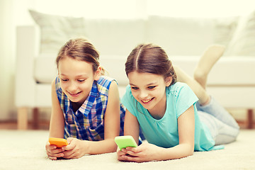 Image showing happy girls with smartphones lying on floor