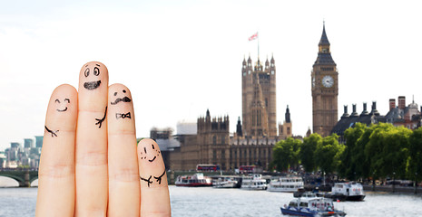 Image showing close up of fingers with smiley faces over london