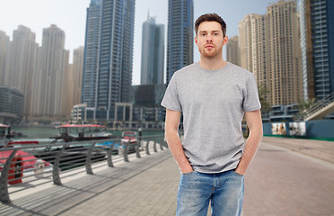 Image showing young man in gray t-shirt and jeans over city 
