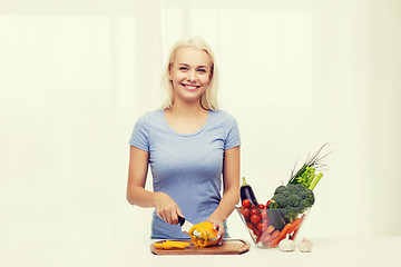 Image showing smiling young woman chopping vegetables at home