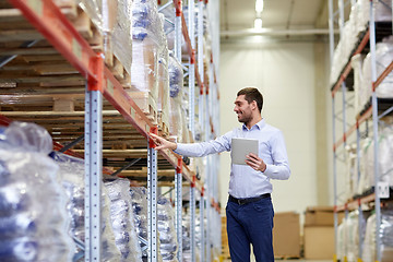 Image showing happy businessman with tablet pc at warehouse