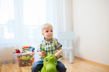 Image showing happy baby boy playing with ride-on toy at home