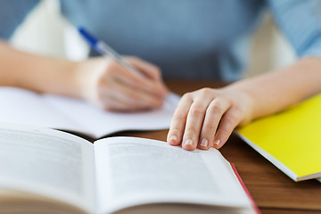 Image showing close up of student with book and notebook at home