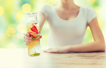 Image showing close up of woman with fruit water in glass bottle