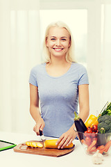 Image showing smiling young woman chopping vegetables at home