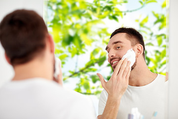 Image showing happy man applying shaving foam at bathroom mirror