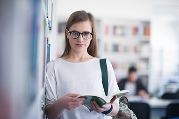 Image showing portrait of famale student reading book in library