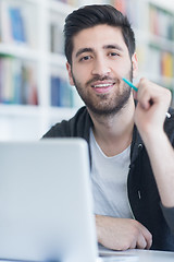 Image showing student in school library using laptop for research