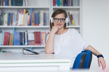 Image showing female student study in library, using tablet and searching for 