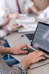 Image showing close up of business man hands typing on laptop with team on mee