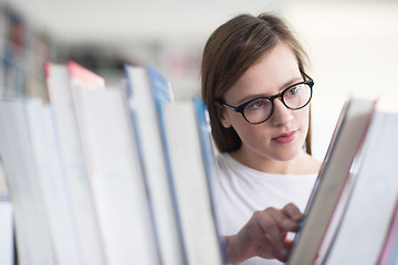 Image showing portrait of famale student selecting book to read in library