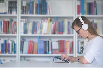 Image showing female student study in library, using tablet and searching for 