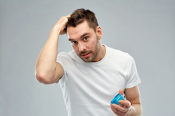 Image showing happy young man styling his hair with wax or gel