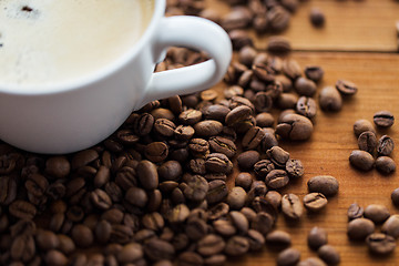 Image showing close up coffee cup and beans on wooden table