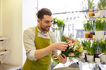 Image showing smiling florist man making bunch at flower shop