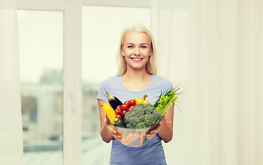 Image showing smiling young woman with vegetables at home