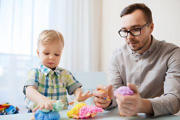 Image showing father and son playing with ball clay at home