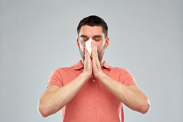 Image showing sick man with paper napkin blowing nose