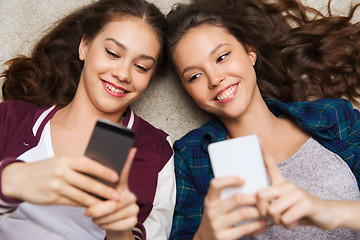 Image showing happy teenage girls lying on floor with smartphone