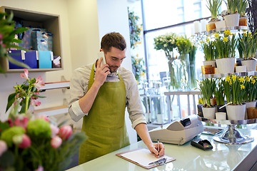 Image showing man with smartphone making notes at flower shop