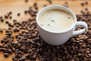 Image showing close up coffee cup and grains on wooden table