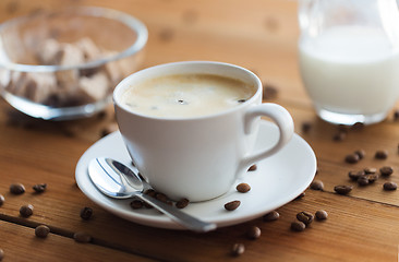 Image showing close up coffee cup and grains on wooden table