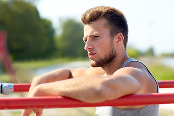 Image showing young man exercising on parallel bars outdoors