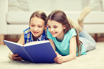 Image showing two happy girls reading book at home