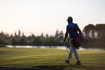 Image showing golfer  walking and carrying golf  bag at beautiful sunset