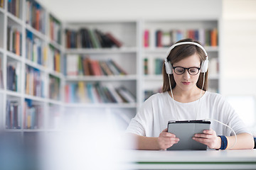 Image showing female student study in library, using tablet and searching for 