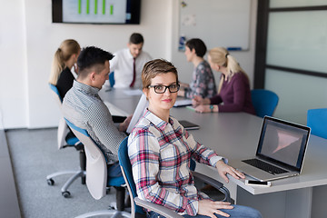 Image showing young business woman at office working on laptop with team on me