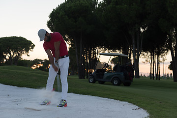 Image showing golfer hitting a sand bunker shot on sunset