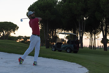 Image showing golfer hitting a sand bunker shot on sunset