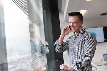 Image showing young business man speaking on  smart phone at office