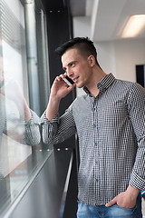 Image showing young business man speaking on  smart phone at office