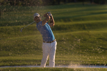 Image showing golfer hitting a sand bunker shot on sunset