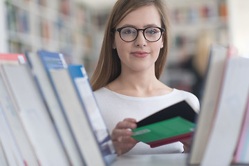 Image showing portrait of famale student selecting book to read in library