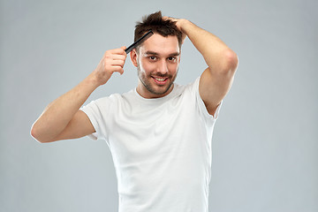 Image showing happy man brushing hair with comb over gray