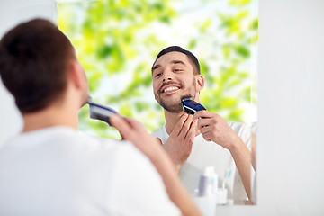 Image showing man shaving beard with trimmer at bathroom